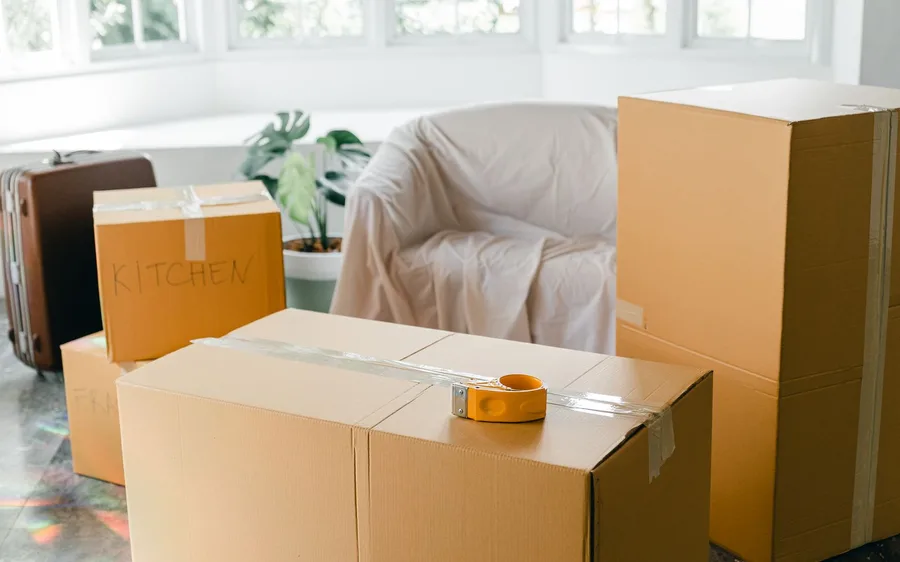Packed moving boxes labelled Kitchen and Fragile in an empty, sunlit room